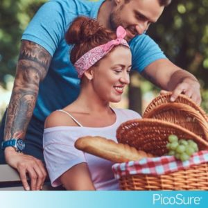 Woman with picnic basket and man behind her with tattooed arm