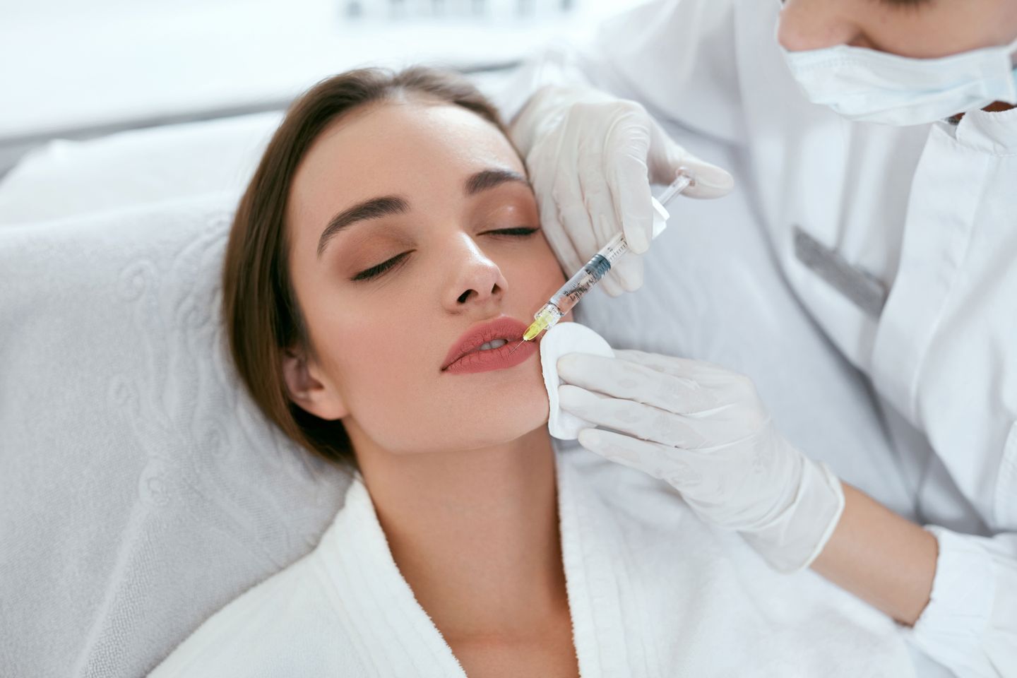 woman receiving a lip filler injection during a cosmetic treatment