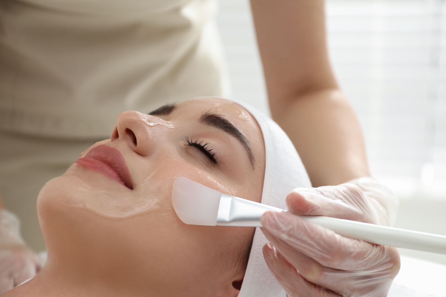 esthetician applying a chemical peel solution to a relaxed womans face